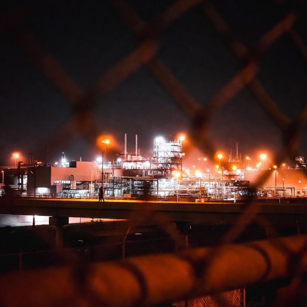 Blurry radioactive Kia factory through fence.
