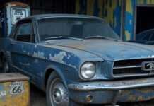 Top 7 Classic Cars That Skyrocketed in Value Over the Years Scratched 1965 Mustang in barn, rusty pump, hubcap.