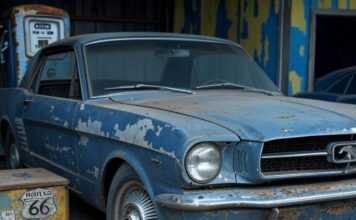Top 7 Classic Cars That Skyrocketed in Value Over the Years Scratched 1965 Mustang in barn, rusty pump, hubcap.